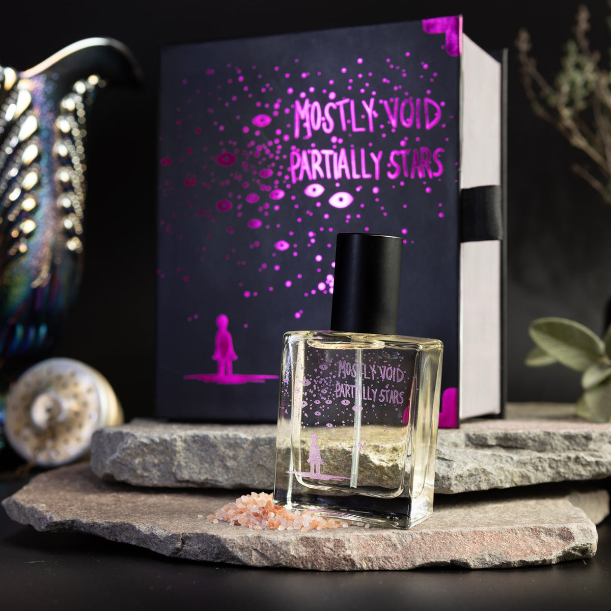 Close-up of Mostly Void, Partially Stars perfume with its purple-foil Night Vale collector's box behind it.