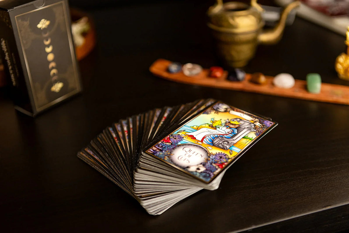 Sucreabeille Wildland Tarot cards fanned across a dark wooden table with candles and stones.